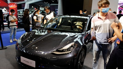 Visitors look at a Tesla Model 3 vehicle on display at an auto show in southwestern China's Chongqing Municipality, June 13, 2020.