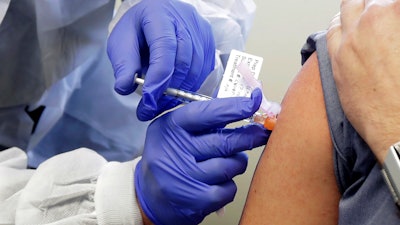 A subject receives a shot in the first-stage safety study clinical trial of a potential vaccine by Moderna for COVID-19 at the Kaiser Permanente Washington Health Research Institute in Seattle, March 16, 2020.