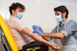 In this handout photo, a doctor takes blood samples for use in a coronavirus vaccine trial in Oxford, England, June 25, 2020.