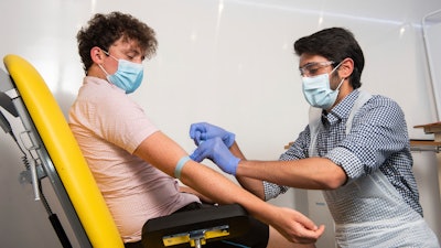 In this handout photo, a doctor takes blood samples for use in a coronavirus vaccine trial in Oxford, England, June 25, 2020.
