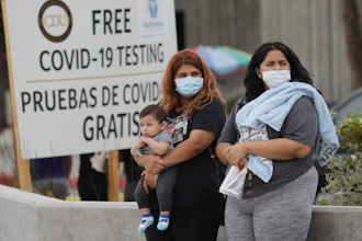 Two women and a child wait to take a coronavirus test at the Charles Drew University of Medicine and Science, July 22, 2020, in Los Angeles.
