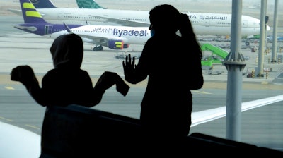 Passengers watch aircraft on the tarmac as they wait for their flight at the King Abdulaziz International Airport in Jiddah, Saudi Arabia, Tuesday, July 28, 2020. Few flights are scheduled for international departures only but the authorities have eased domestic travel restrictions since June.