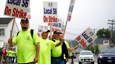 Picketers acknowledge a honking motorist outside an entrance to Bath Iron Works, Monday, June 22, 2020, in Bath, Maine. Production workers at one of the Navy's largest shipbuilders overwhelmingly voted to strike, rejecting the company's three-year contract offer Sunday and threatening to further delay delivery of ships.