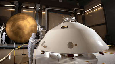 Lockheed Martin engineers work on the construction of the aeroshell for the Mars 2020 mission. The cone-shaped back shell and orange heat shield will protect the Perseverance rover on its way to the surface of Mars.