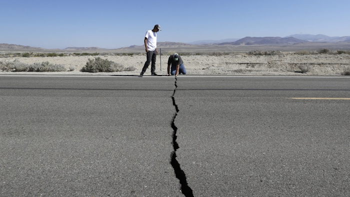 Ron Mikulaco, right, and Brad Fernandez examine a crack caused by an earthquake on Highway 178 outside Ridgecrest, Calif., July 6, 2019.