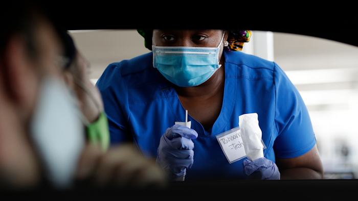 Healthcare worker Rahaana Smith instructs passengers at a drive-thru COVID-19 testing site at the Miami-Dade County Auditorium, Miami, July 24, 2020.
