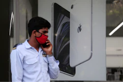 A security officer talks on a phone in front of an image of an iPhone displayed at an Apple store in Ahmedabad, India.