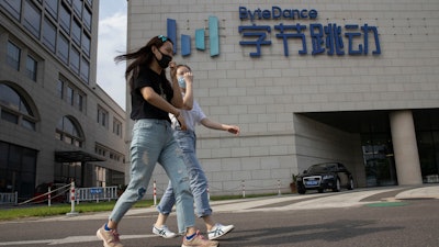 Women wearing masks pass by the ByteDance headquarters in Beijing, Aug. 7, 2020.
