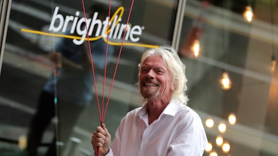 Richard Branson, of Virgin Group, prepares to unfurl a banner during a naming ceremony for the Brightline train station.