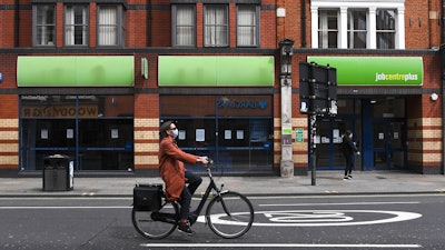A woman rides a bicycle past a job center in Shepherd's Bush, London, April 30, 2020.