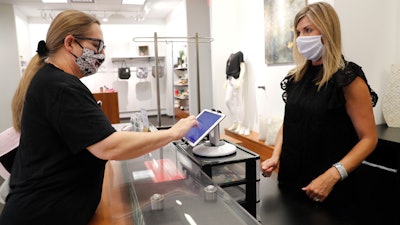 Monique Kursar, left, completes a purchase with Amy Witt, owner of the Velvet Window clothing store in Dallas, May 13, 2020.