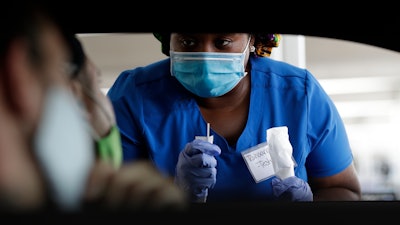 Healthcare worker Rahaana Smith instructs passengers at a drive-thru COVID-19 testing site at the Miami-Dade County Auditorium, Miami, July 24, 2020.
