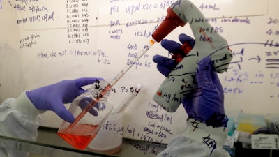 Research associate Kai Hu transfers medium to cells in a laboratory at Imperial College in London, July 30, 2020.