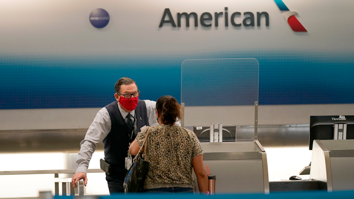 American Airlines ticket agent Henry Gemdron, left, works with a customer at Miami International Airport, Sept. 30, 2020.