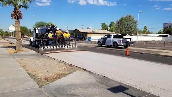 A City of Phoenix Street Transportation Department crew sprays light-colored pavement over blacktop on a street in the Garfield District of Phoenix, Aug. 11, 2020.