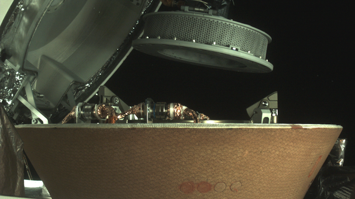In this undated image provided by NASA, a sample container hovers over a capsule on the Osiris-Rex spacecraft near the asteroid Bennu.