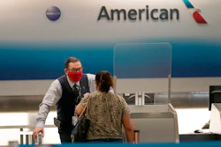 American Airlines ticket agent Henry Gemdron, left, works with a customer at Miami International Airport, Sept. 30, 2020.