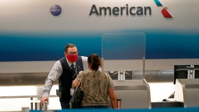 American Airlines ticket agent Henry Gemdron, left, works with a customer at Miami International Airport, Sept. 30, 2020.