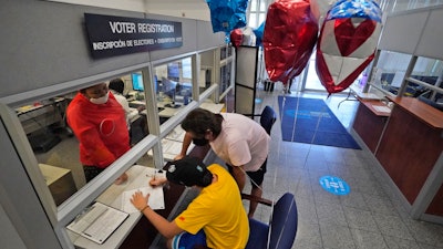 Lucas Saez, 22, fills out his voter registration form as his father Ramiro Saez looks on at the Miami-Dade County Elections Department, Doral, Fla., Oct. 6, 2020.