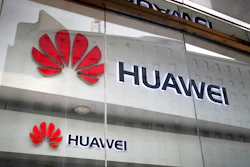 Logos of Huawei are displayed at its retail shop window with the reflection of the Ministry of Foreign Affairs office in Beijing.