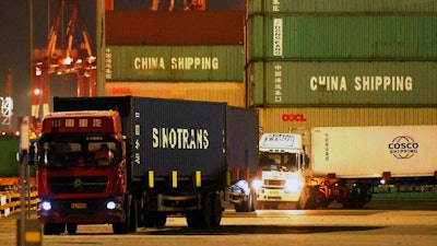 Trucks transport shipping containers at a dockyard in Qingdao in east China's Shandong province.