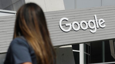 A woman walks below a Google sign on the campus in Mountain View, Calif.