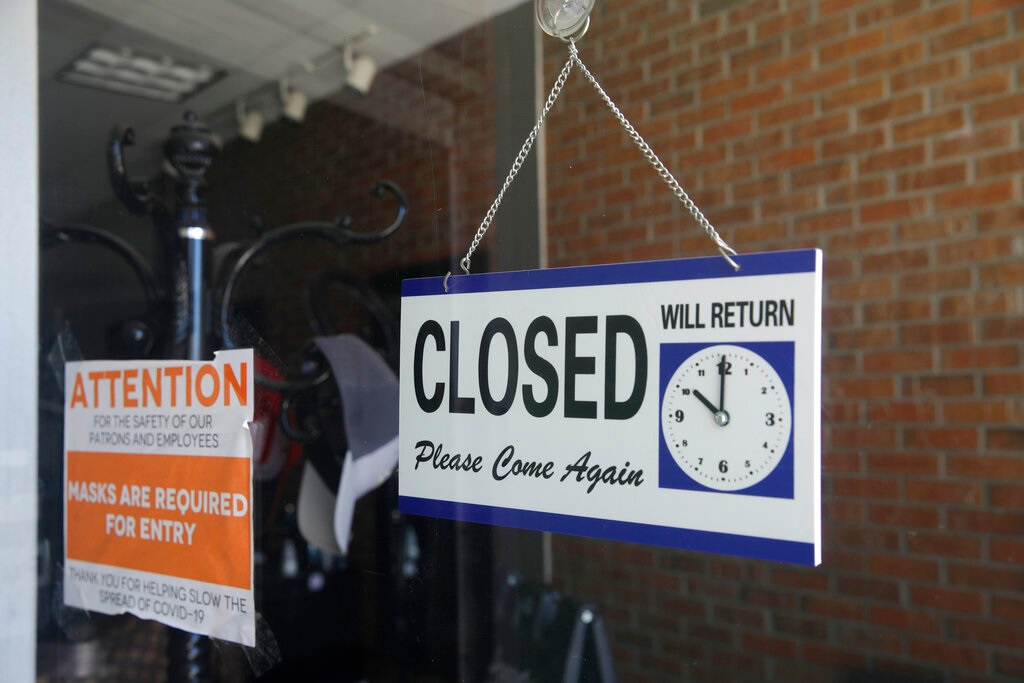 In this July 18, 2020 file photo a closed sign hangs in the window of a barber shop in Burbank, Calif. A critical snapshot of the job market and the economy to be released Friday, Oct. 2, is expected to show a further deceleration in hiring as the nation&rsquo;s viral caseload creeps higher just as financial aid from the government has faded.