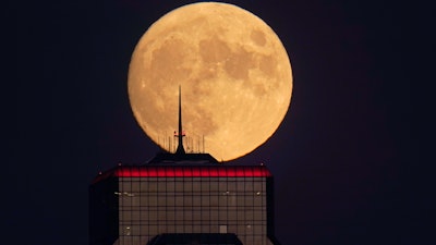 A nearly full moon rises behind an office building in Kansas City, Mo., Sept. 30, 2020.
