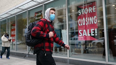 A passer-by walks past a store closing sign in Boston, Oct. 27, 2020.