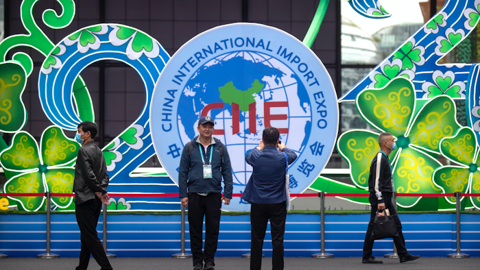 A visitor poses for photos in front of a display at the China International Import Expo in Shanghai, Nov. 5, 2020.