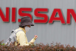 A woman walks past the corporate logo at Nissan Motor Co.'s global headquarters in Yokohama, near Tokyo, on May 21, 2020.