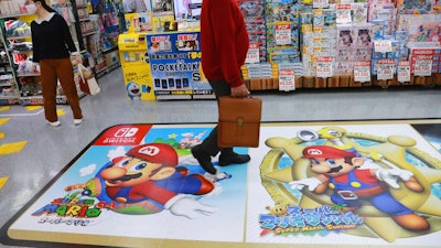 A shopper passes by an ad for Super Mario of Nintendo at an electronics store in Tokyo.