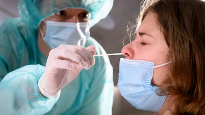 A health worker collects a nose swab sample for a polymerase chain reaction test at the Mycorama coronavirus testing facility, Cernier, Switzerland, Nov. 3, 2020.
