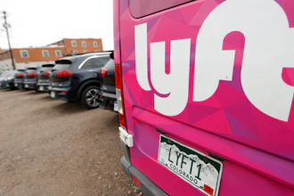 Kia Neros that are part of the Lyft ride-hailing fleet sit in a lot near Empower Field at Mile High in Denver, April 30, 2020.