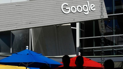 People walk by a Google sign on its campus in Mountain View, Calif., Sept. 24, 2019.