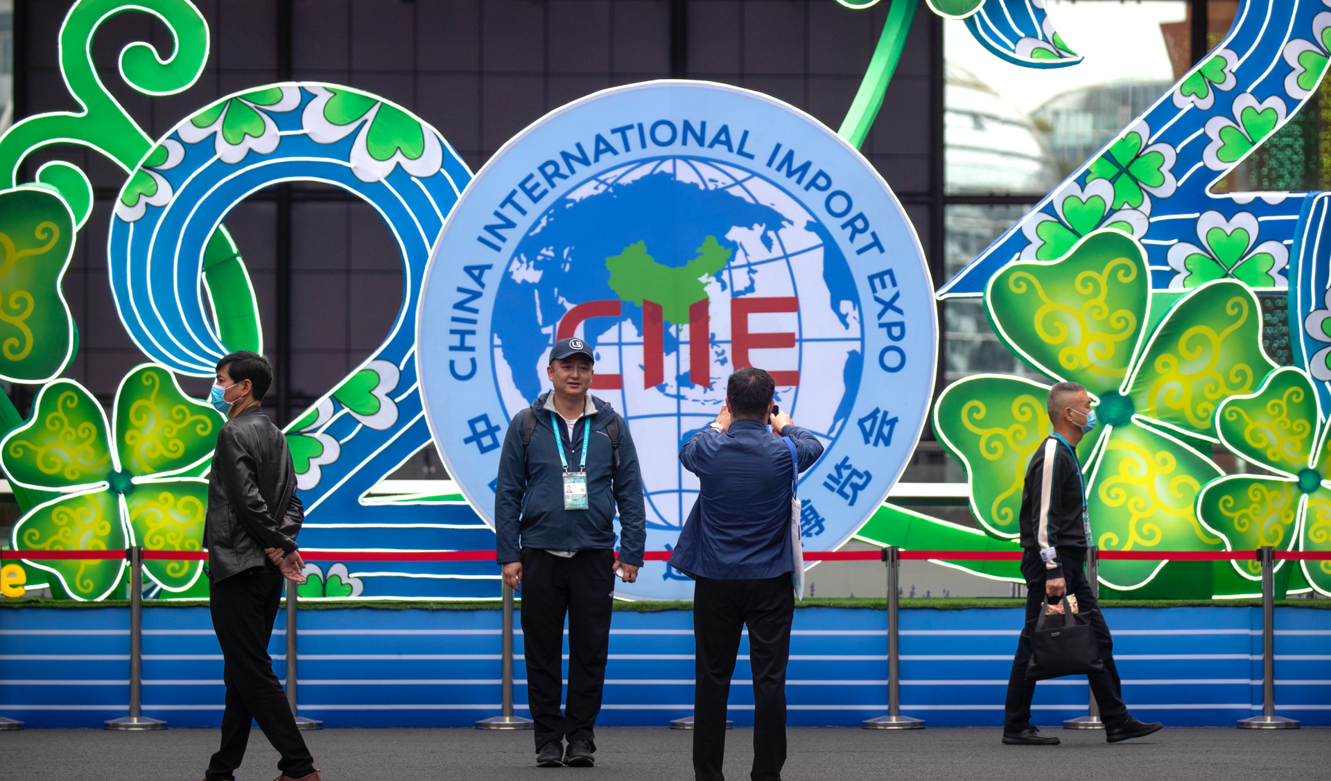 A visitor poses for photos in front of a display at the China International Import Expo in Shanghai, Nov. 5, 2020.