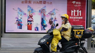 A delivery man passes by an ad for the Nov. 11 Sales Day in Beijing, Oct. 28, 2020.