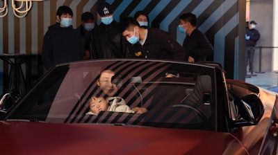 A woman exits a car on display during a promotion held in a popular shopping district in Beijing, Nov. 8, 2020.