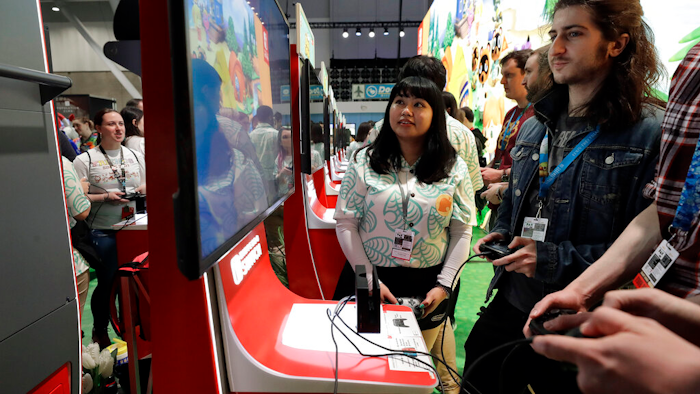 Visitors to the Pax East conference play the Nintendo Switch video game Animal Crossing, Feb. 27, 2020, in Boston.