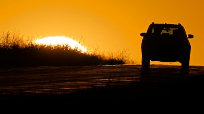 A motorist drives into the sunrise in Kansas City, Mo., Oct. 1, 2020.