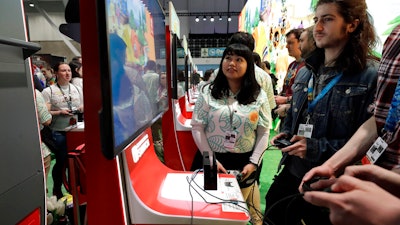Visitors to the Pax East conference play the Nintendo Switch video game Animal Crossing, Feb. 27, 2020, in Boston.