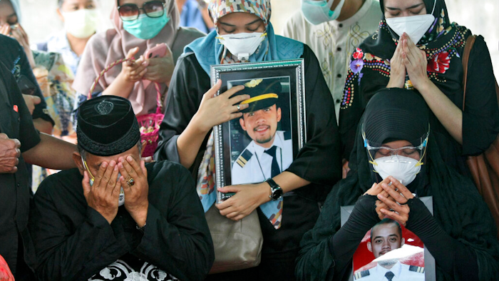 Relatives pray during the burial of Fadly Satrianto, a victim of the crash of Sriwijaya Air flight SJ-182, Surabaya, East Java, Indonesia, Jan. 15, 2021.