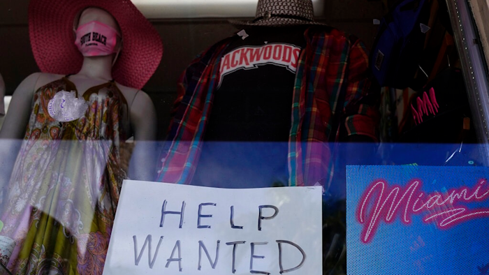 A 'Help Wanted,' sign is shown in the window of a souvenir shop, Thursday, Jan. 7, 2021, in Miami Beach, Fla. Layoffs spiked in November compared with the previous month and the number of job openings slipped, a sign the job market has stalled as the resurgent coronavirus has forced new shutdowns of restaurants and bars and discouraged consumer spending.
