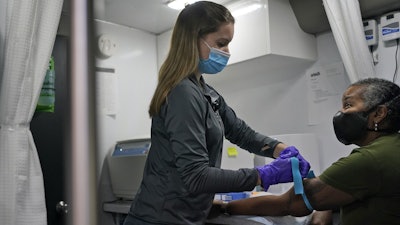 Nurse Brianne Stockman prepares to draw blood from study participant Lani Muller in a mobile medical unit, Queens, New York, Jan. 5, 2021.