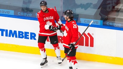 Canada's Braden Schneider (2) and Philip Tomasino (26) celebrate a goal against Switzerland during the first period of an IIHF World Junior Hockey Championship game in Edmonton, Alberta, Dec. 29, 2020.