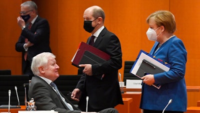 Chancellor Angela Merkel walks beside Finance Minister Olaf Scholz and Interior Minister Horst Seehofer prior to a cabinet meeting, Jan. 6, 2021, the Chancellery, Berlin.