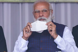Indian Prime Minister Narendra Modi holds a face mask as he attends a rally in Sivsagar, India, Jan. 23, 2021.