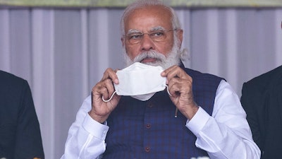 Indian Prime Minister Narendra Modi holds a face mask as he attends a rally in Sivsagar, India, Jan. 23, 2021.