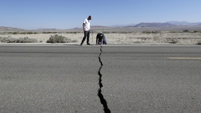 Ron Mikulaco, right, and his nephew, Brad Fernandez, examine a crack caused by an earthquake on Highway 178 outside of Ridgecrest, Calif., July 6, 2019.