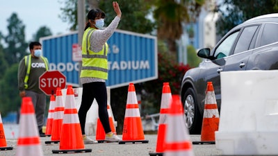 Cars are waved in as people arrive to receive the COVID-19 vaccine at Dodger Stadium, Los Angeles, Feb. 1, 2021.